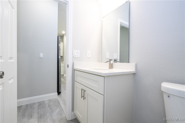 bathroom featuring vanity, hardwood / wood-style flooring, and toilet