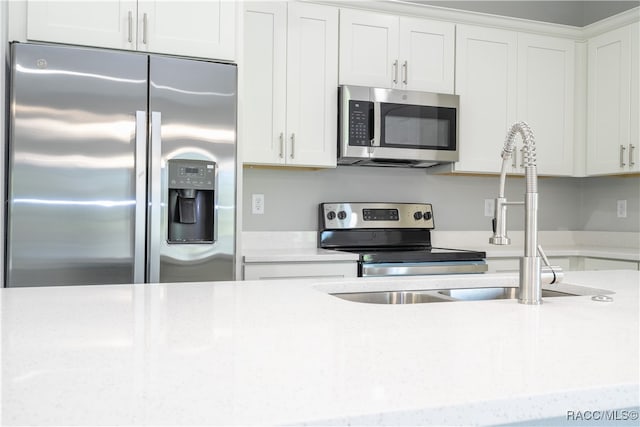 kitchen with white cabinetry, light stone countertops, and appliances with stainless steel finishes