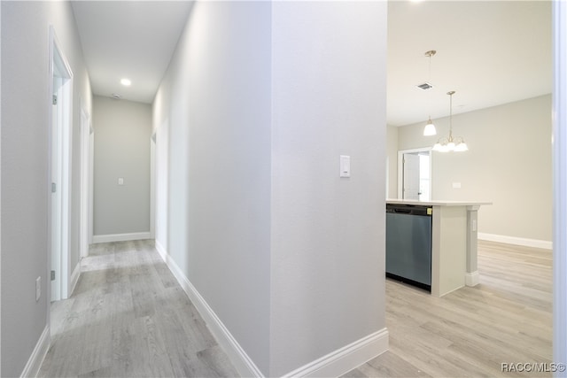 hallway with a chandelier and light wood-type flooring