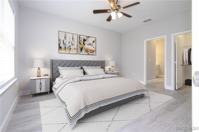 bedroom with ceiling fan, light wood-type flooring, a spacious closet, connected bathroom, and a closet