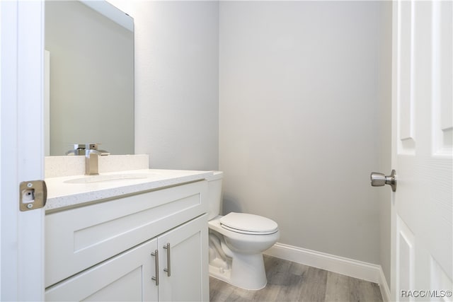 bathroom with toilet, vanity, and hardwood / wood-style flooring