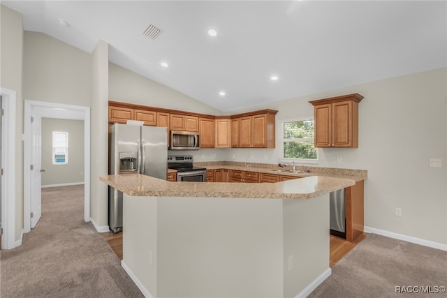 kitchen with light carpet, stainless steel appliances, vaulted ceiling, sink, and a kitchen island