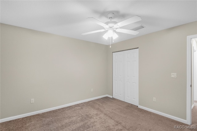 unfurnished bedroom featuring ceiling fan, light colored carpet, and a closet