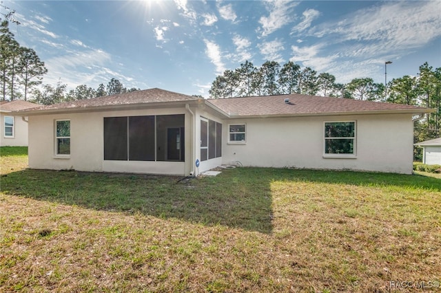 rear view of house with a lawn and a sunroom