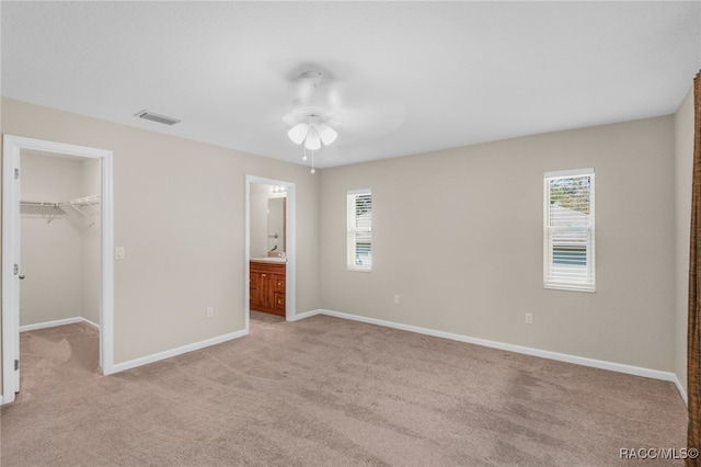 unfurnished bedroom featuring ceiling fan, a closet, a spacious closet, and multiple windows