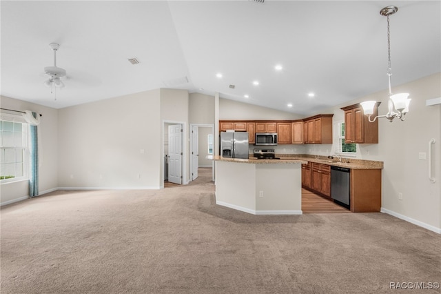 kitchen featuring ceiling fan with notable chandelier, hanging light fixtures, vaulted ceiling, appliances with stainless steel finishes, and a kitchen island