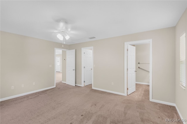 unfurnished bedroom with a closet, light colored carpet, and ceiling fan