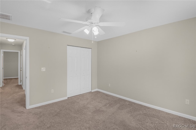 unfurnished bedroom with ceiling fan, light colored carpet, and a closet