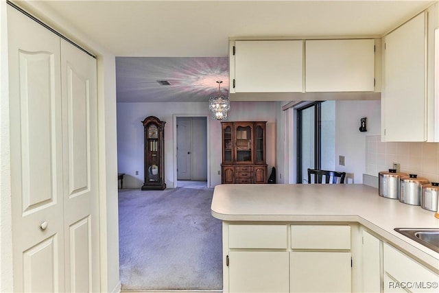 5618 W Hesse Ct, Homosassa, FL 34448 - kitchen featuring light carpet, a peninsula, light countertops, backsplash, and an inviting chandelier