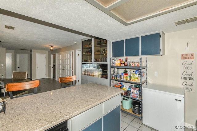 640 E Hartford St, Hernando, FL 34442 - kitchen with fridge, light tile patterned flooring, blue cabinetry, a textured ceiling, and light countertops
