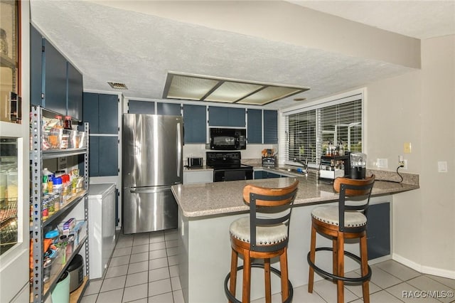 640 E Hartford St, Hernando, FL 34442 - kitchen with black appliances, light tile patterned floors, a peninsula, blue cabinetry, and light stone countertops