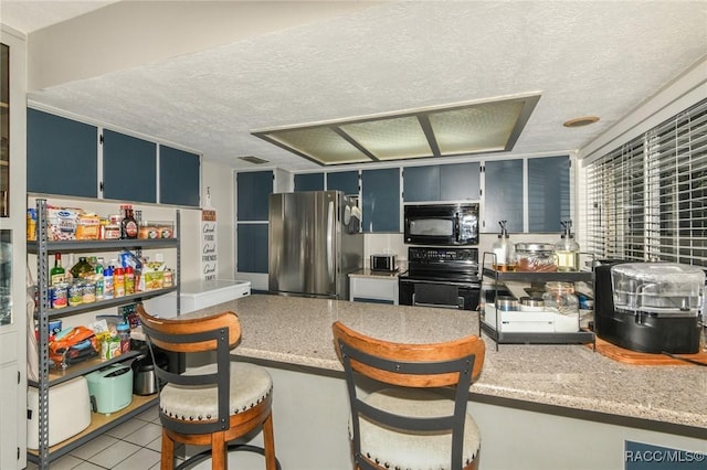640 E Hartford St, Hernando, FL 34442 - kitchen with black appliances, a textured ceiling, a breakfast bar, blue cabinetry, and light tile patterned floors