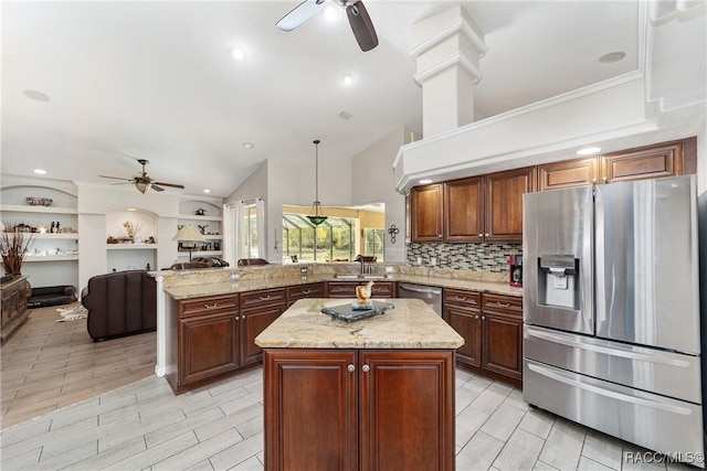 kitchen featuring light stone countertops, appliances with stainless steel finishes, a center island, decorative light fixtures, and kitchen peninsula