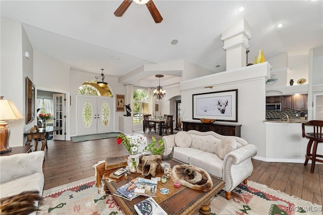 living room with ceiling fan with notable chandelier, hardwood / wood-style floors, and french doors