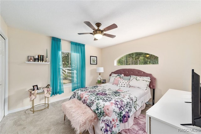 bedroom with ceiling fan, multiple windows, and light carpet