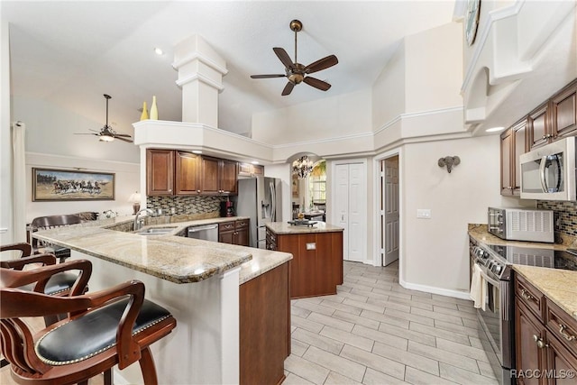 kitchen with a center island, a towering ceiling, stainless steel appliances, kitchen peninsula, and a breakfast bar