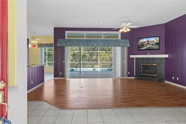 unfurnished living room with hardwood / wood-style floors, ceiling fan, and a tiled fireplace