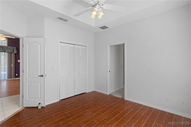 empty room featuring wood-type flooring, a tray ceiling, and ceiling fan