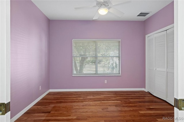 unfurnished bedroom with dark hardwood / wood-style flooring, a closet, and ceiling fan