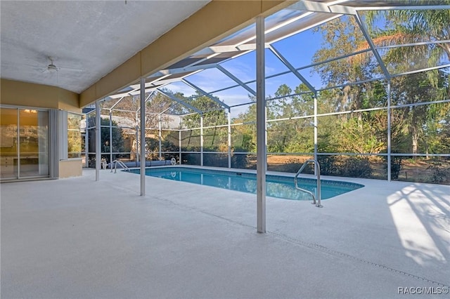 view of swimming pool with a patio, ceiling fan, and glass enclosure