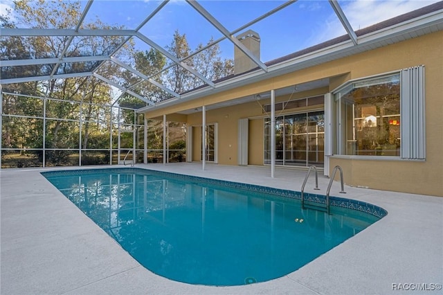 view of pool with glass enclosure and a patio