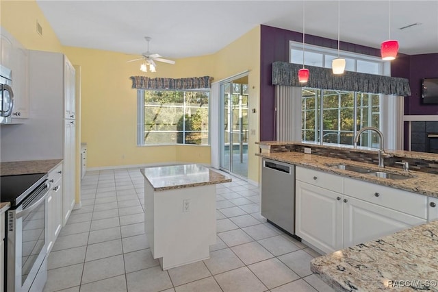 kitchen with pendant lighting, sink, appliances with stainless steel finishes, light stone counters, and white cabinetry