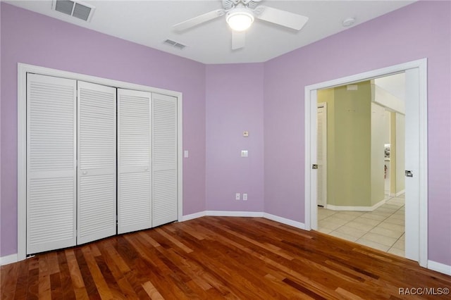 unfurnished bedroom with wood-type flooring, a closet, and ceiling fan