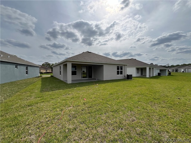 back of property with central air condition unit and a yard