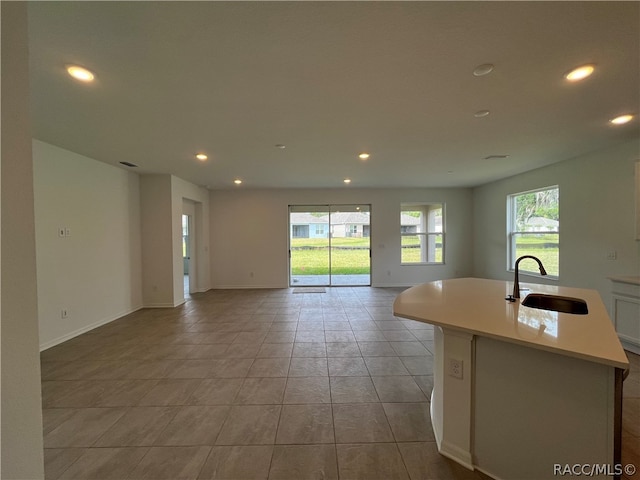 kitchen featuring a wealth of natural light, a kitchen island with sink, sink, and light tile patterned floors