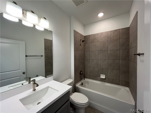 full bathroom featuring vanity, tiled shower / bath combo, and toilet