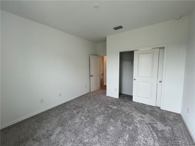 unfurnished bedroom featuring dark colored carpet and a closet