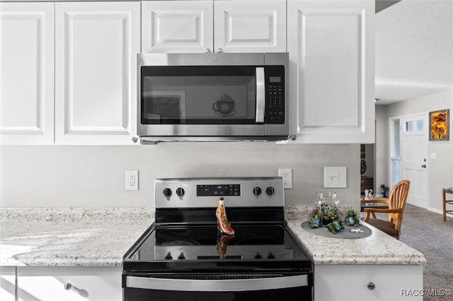 kitchen with white cabinets, light stone counters, and stainless steel appliances