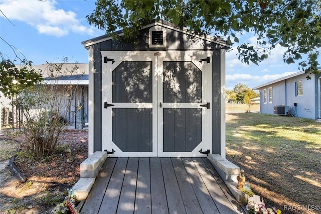 view of outbuilding featuring cooling unit and a lawn