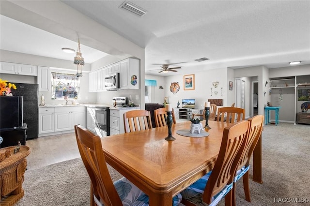 dining space featuring ceiling fan, sink, and light colored carpet