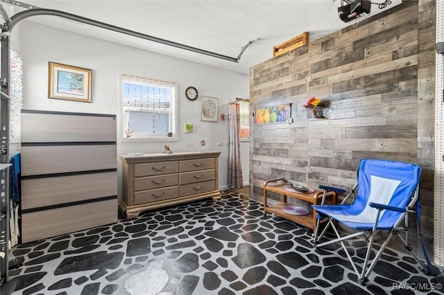 living area featuring wood walls and a textured ceiling