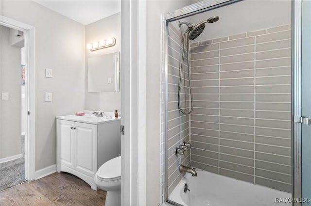 full bathroom with hardwood / wood-style floors, vanity, tiled shower / bath combo, and toilet