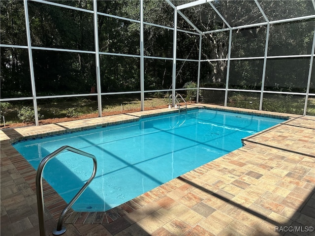 view of swimming pool with a patio area and a lanai