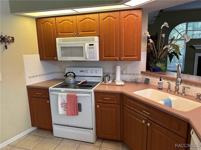 kitchen with decorative backsplash, light tile patterned floors, white appliances, and sink