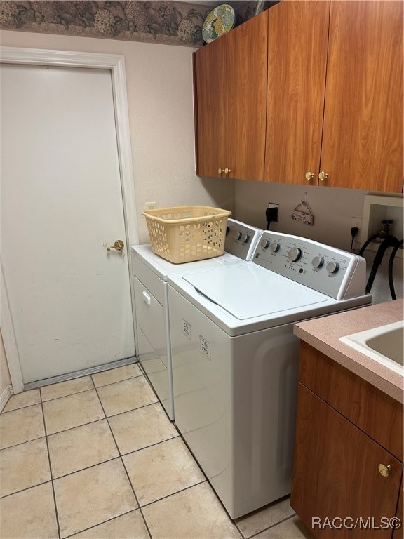 laundry room featuring cabinets, light tile patterned floors, and washing machine and clothes dryer