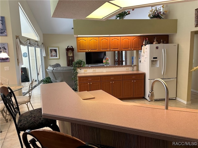 kitchen with kitchen peninsula, vaulted ceiling, white fridge with ice dispenser, and light tile patterned flooring