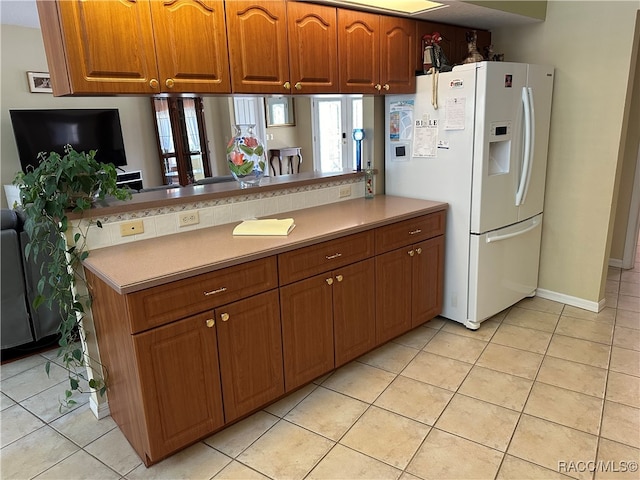 kitchen featuring kitchen peninsula, white fridge with ice dispenser, and light tile patterned floors