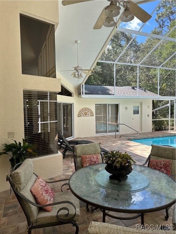 exterior space with ceiling fan, a patio area, and glass enclosure