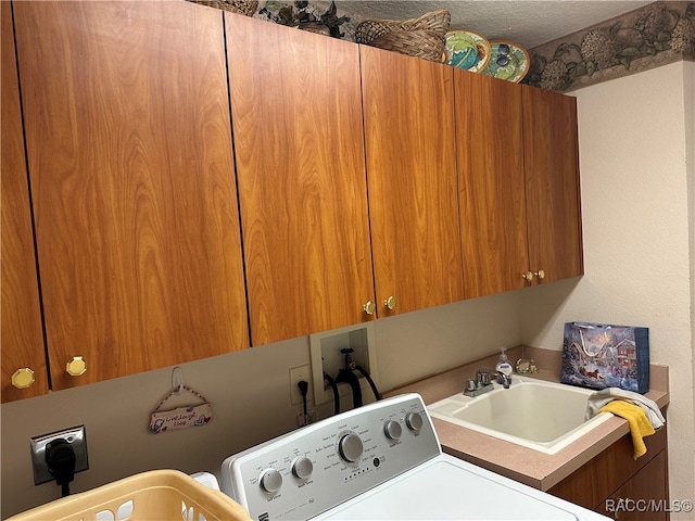 washroom with sink, cabinets, a textured ceiling, and washer / dryer