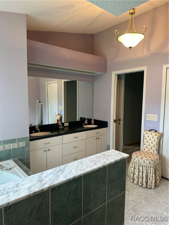 bathroom with a tub, tile patterned flooring, a textured ceiling, lofted ceiling, and vanity