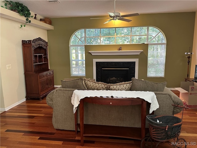 living room featuring a textured ceiling, plenty of natural light, ceiling fan, and dark wood-type flooring