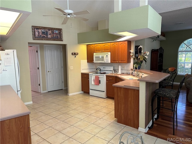 kitchen featuring kitchen peninsula, a textured ceiling, white appliances, and ceiling fan