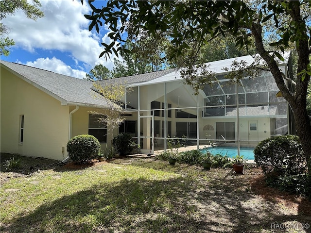 back of property with a lawn and glass enclosure