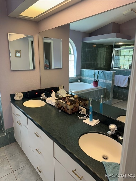 bathroom featuring tile patterned flooring, vanity, and a tile shower