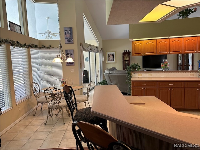 kitchen with plenty of natural light, light tile patterned floors, pendant lighting, and ceiling fan with notable chandelier