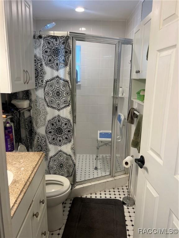 bathroom featuring walk in shower, tile patterned floors, vanity, and toilet